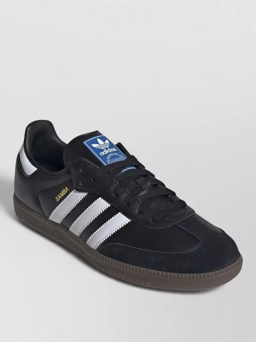 Adidas Originals Leather low-top sneakers — The black Samba grounds the outfit in classic terrace streetwear, echoing the cap’s branding and working perfectly with the athletic mini short for a cohesive sporty vibe.