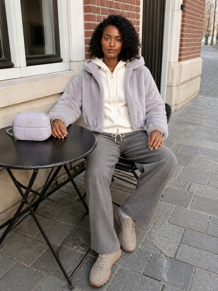 I am building around the bomber with a top and trouser rather than a dress, to echo its sporty-cropped proportions and keep the faux fur as the clear focal point. Cool-toned ivory and grey underneath keep the palette hushed and graphic, while the taupe runner and lilac pouch introduce just enough warmth and personality to feel intentional rather than loungey. The result is a cocooned, city-ready ensemble that reads relaxed but considered from head to toe.