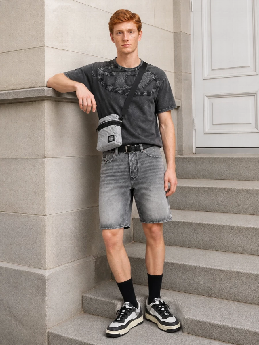 Washed greys and charcoals keep this outfit tight and urban, with the distressed tee and bermudas doing the attitude work. Chunky but clean sneakers and a compact technical crossbody lean into a utility streetwear feel, while the black belt quietly frames the shorts so the fading and texture stay the focus.