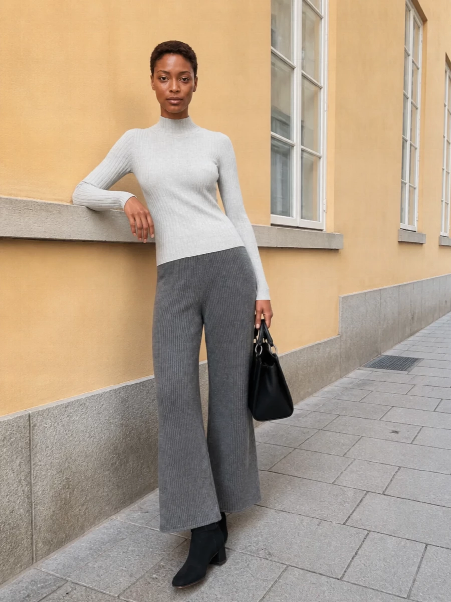 Soft silver rib and charcoal knit trousers create a long, tonal line that feels quietly precise rather than casual. Block-heel boots and a structured black bag sharpen the softness just enough, keeping the outfit city-ready while still cocooned in texture.