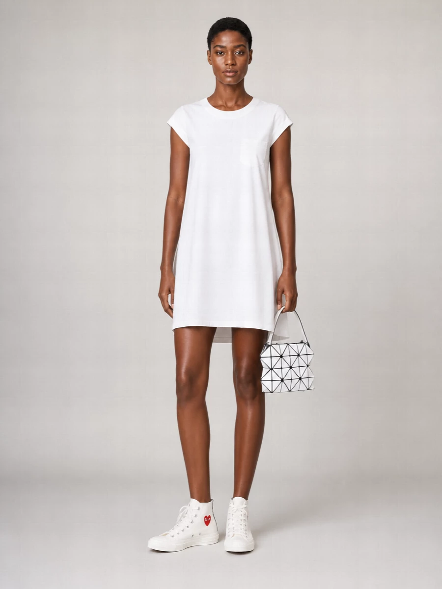 I chose the dress path so the sneakers can sit against one clean, uninterrupted line rather than competing with separates, which keeps the mood minimal and graphic. The Sacai white mini shift pairs with the Comme des Garçons high tops in a crisp, almost mod way, letting the red heart and black foxing be the only strong accents. The Bao Bao geometric mini bag picks up that black and white story with a sharper edge, turning a simple tee-dress-and-sneakers combination into something that feels quietly designed and city ready.