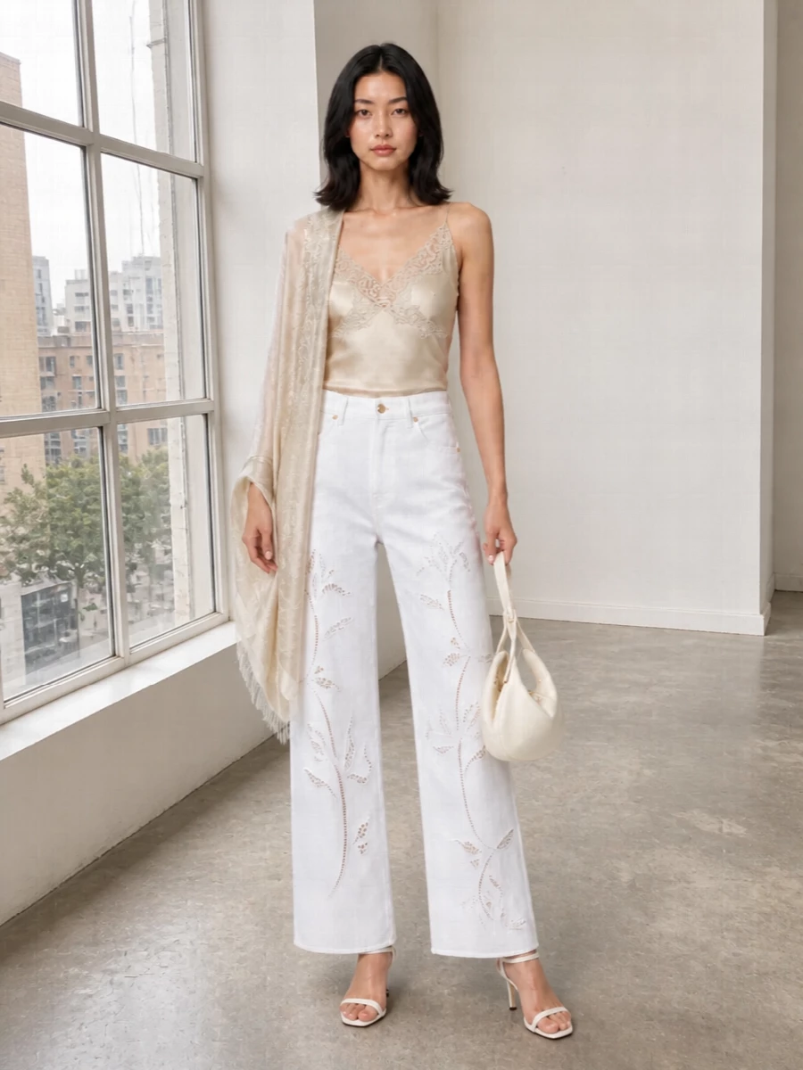White embroidered denim meets liquid champagne satin for a monochrome summer mood that feels airy, romantic and quietly precise. The slim camisole and delicate sandals balance the wide-leg proportion, keeping the line long and clean. An off-white sculptural bag and tonal paisley stole add just enough texture for terrace dinners and gallery evenings without disturbing the calm palette.