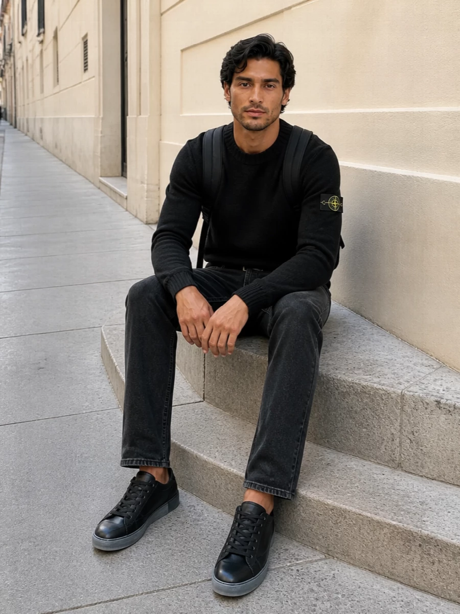Washed black Stone Island denim and the brand’s black crew knit create a tight monochrome base that feels technical, urban and quietly precise. The Dolce&Gabbana sneakers keep it agile and street-led, while a low-key Stone Island backpack and structured black belt finish the outfit with practical detail that stays firmly in the minimalist lane.