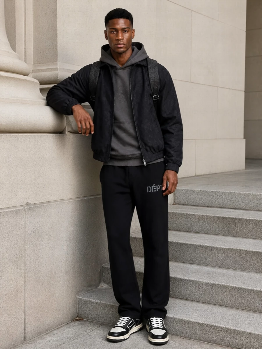 Tonal blacks and charcoals build a low-key luxury streetwear uniform around Gucci’s stealth-logo shell, with Represent and Gallery Dept adding lived-in, studio energy. Amiri courts and an Etro paisley backpack keep the palette tight but textured, so the whole outfit feels graphic without a single loud color. It is an off-duty city setup that moves easily from coffee runs to late-night flights while staying firmly in the designer lane.