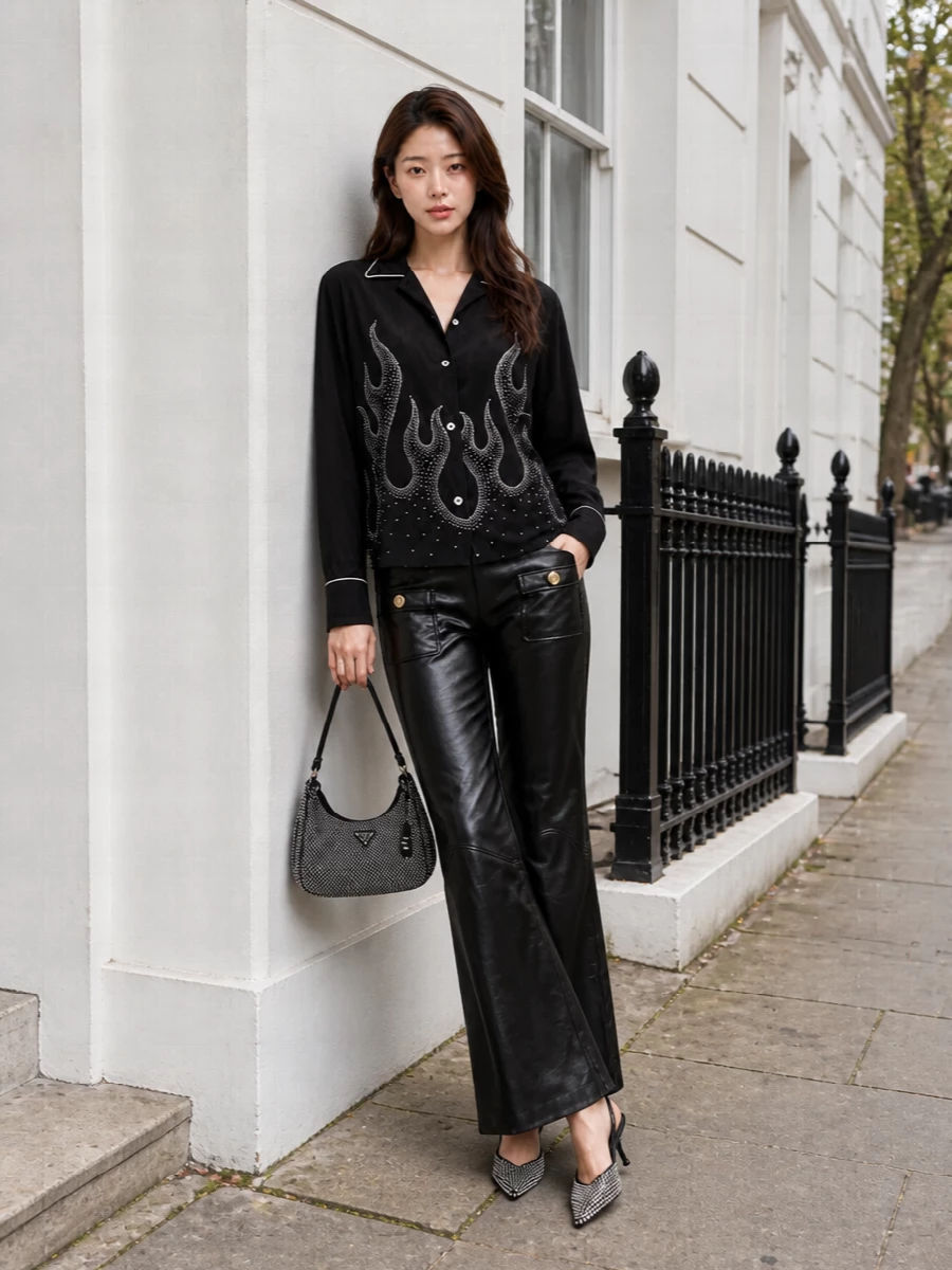 A crystal-flame Palm Angels shirt meets glossy black flares for a night-out uniform that feels glam but still grounded in street attitude. The razor-sharp crystal slingbacks and Prada rhinestone baguette double down on light play without breaking the strict black palette. It is an all-black, high-shine take on Y2K that reads deliberate, polished and built for after-dark city energy.