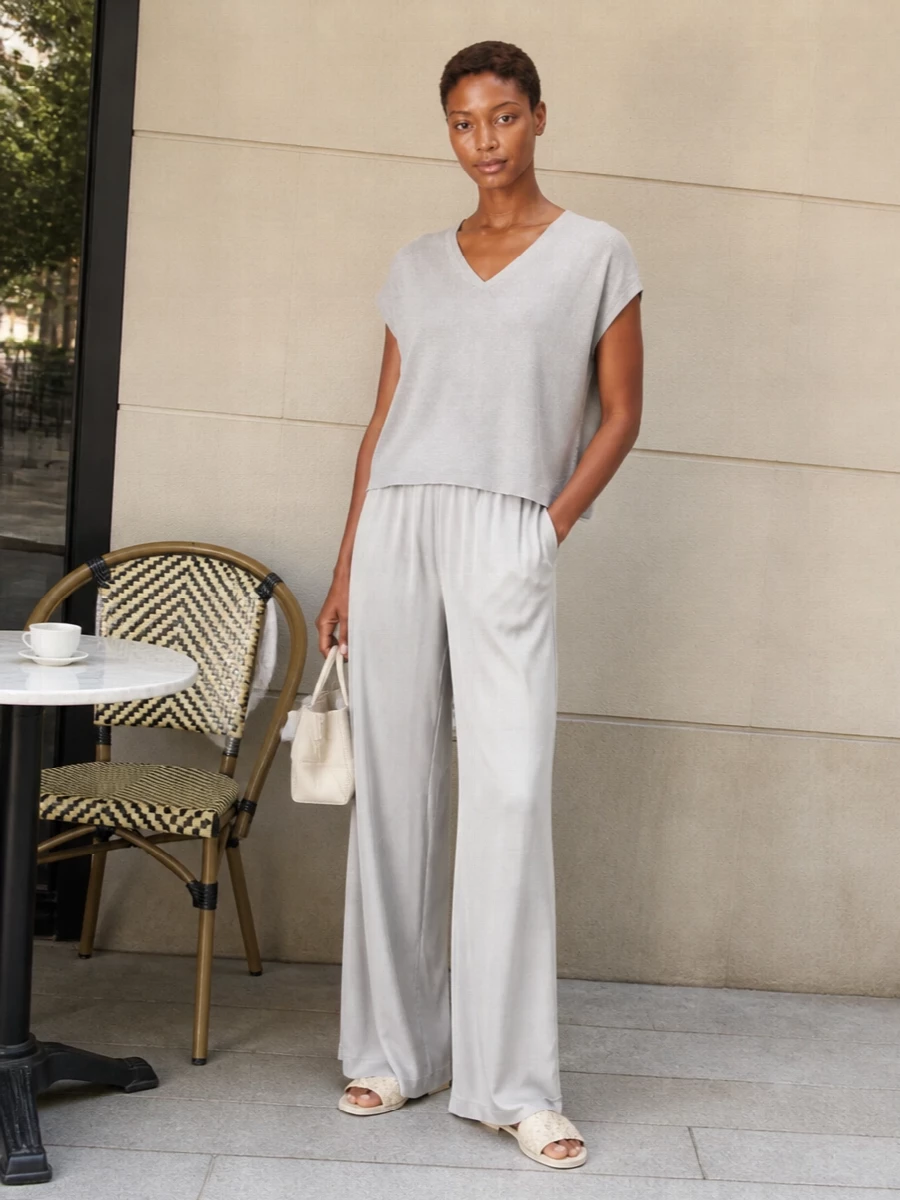 Soft light grey and pearl tones create a long, clean column that feels calm and put-together without trying. The relaxed knit and fluid wide leg work together to skim rather than cling, ideal for warm days when you still want polish. Cream slides and a small ivory bag keep the palette quiet and refined, so the focus stays on proportion and movement.