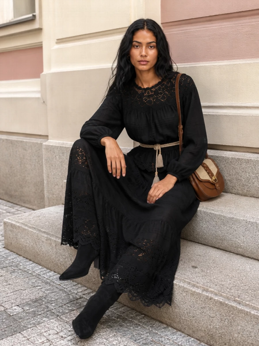 An all‑black Isabel Marant Étoile pairing turns broderie anglaise into something quietly dramatic, with the gathered blouse flowing into a sheer tiered maxi. The cone‑heel ankle boots add just enough height to keep the volume elegant rather than heavy, while tan leather and raffia at the shoulder and a braided belt at the waist bring soft, sun‑worn warmth back into the palette. It is romantic, bohemian and polished enough to move from late lunch to terrace cocktails without a change.