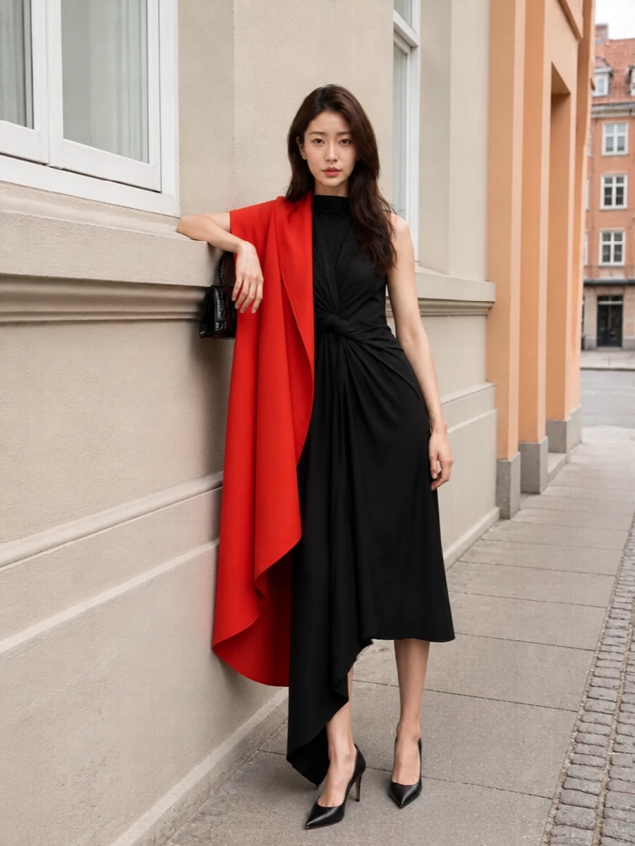 I am taking the dress route here so the cape can remain the single dramatic outer layer, using a black asymmetric midi as a quiet architectural base rather than fighting it with extra tailoring. The result is a graphic column in black punctuated by that sweep of orange, finished with razor-sharp pumps and a structured mini bag that keep the whole composition clean, strong and gallery-evening ready. All the interest is in cut and line, not print or color, which feels right for this level of Balenciaga severity.