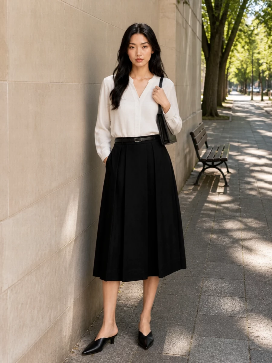 Soft ivory and deep black keep the palette pared back, letting the pleated skirt and V-neck blouse do the quiet work of structure and movement. A pointed kitten-heel mule and slim rectangular shoulder bag sharpen the silhouette for dinners, openings, and city evenings that need polish without fuss. The slim belt is there if you want a little extra definition at the waist, nothing more, nothing less.