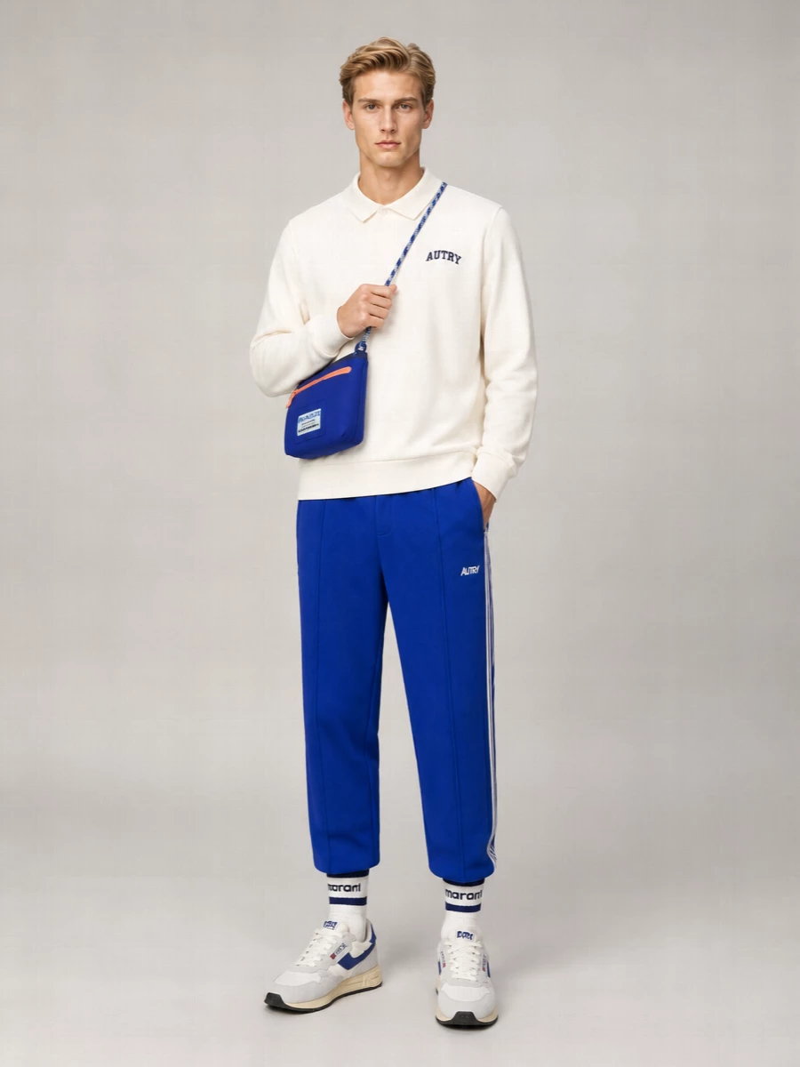Royal blue track pants meet a clean off-white polo for a fresh, collegiate spin on sport. Retro runners echo the blue hits while keeping the base light. A sharp cobalt crossbody and striped socks dial up the athletic color story without feeling busy.
