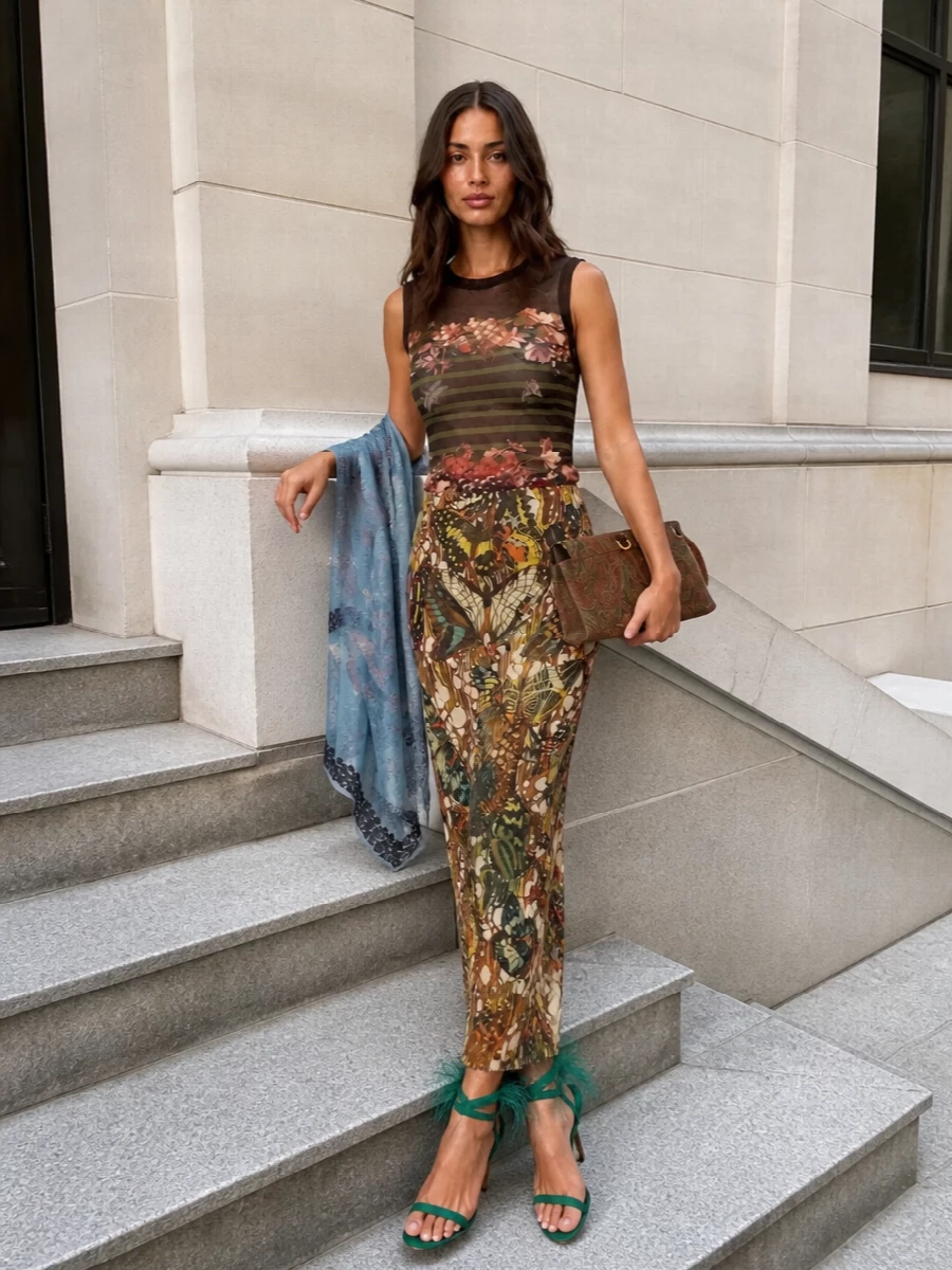 A collectible Gaultier mesh pairing lets the butterfly-print skirt stay hero, anchored by a moody floral tank in the same sensual, second‑skin language. Teal feathered stilettos and an Etro paisley clutch pick up the skirt’s jewel tones, while a gossamer stole adds a final, poetic whisper of colour. The result is a long, lean evening silhouette that feels archival, romantic and distinctly Y2K without ever tipping into costume.
