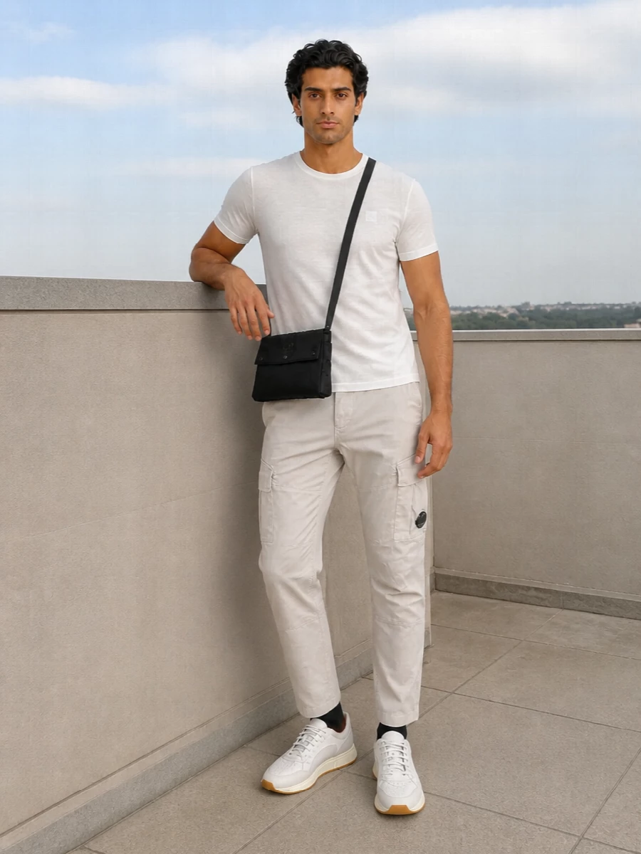An off-white C.P. Company tee sits over light-stone cargos for a clean, technical take on neutrals that still feels easy and relaxed. Soft white gum-sole sneakers keep the line streamlined, while a black crossbody and tonal socks add just enough contrast for an urban, sport-leaning finish.