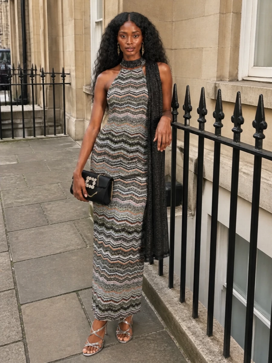 A body-skimming Missoni halter dress stays firmly in the spotlight, framed by liquid silver stilettos and a concise black crystal buckle bag. Gold monogram earrings and a subtle monochrome scarf add just enough glow and texture for a polished night-out finish.