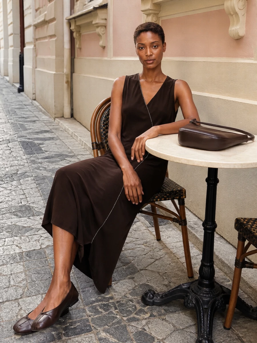 Anchoring the outfit with the Jil Sander chocolate midi allows the Margiela tabi ballerinas to read as a deliberate, tonal statement rather than competing with tailored separates. The result is a slim, asymmetric column in deep brown that feels quietly sensual and polished, with the curved Jacquemus shoulder bag echoing the same rich hue for a cohesive, minimalist finish. Choosing the dress route over top-and-trouser keeps the silhouette ultra-clean and lets the subtle details and textures do the work.