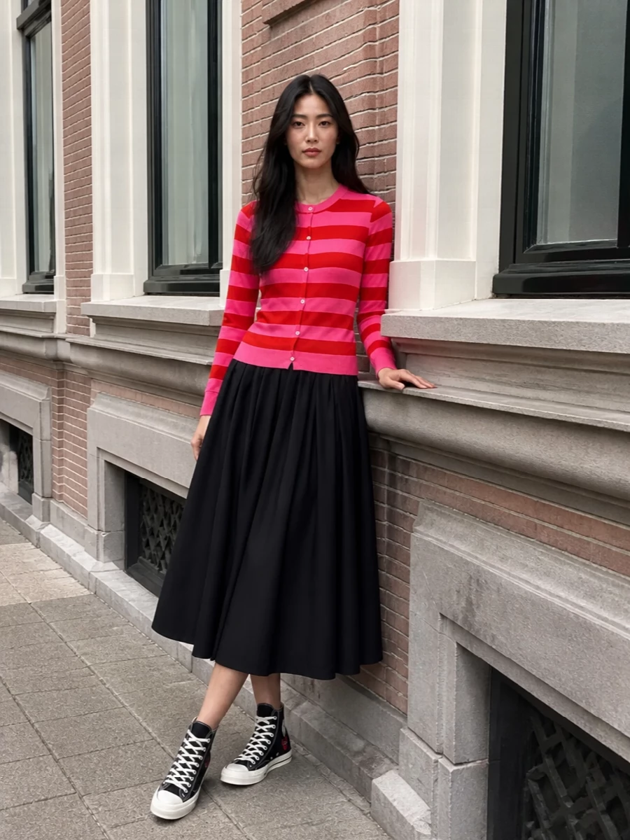 Graphic and upbeat, this mix pairs the striped cardigan with a sculptural black midi, leaning into Comme des Garçons’ play on volume and color. Black Play high-tops and a sharp mini top-handle keep the palette tight and city ready, while a cherry gingham scarf adds a light, witty nod to the red story. The result feels preppy and street at once, polished enough for creative days but relaxed enough for weekend wandering.