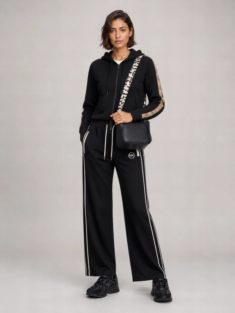 I’m styling the Burberry hoodie as the only top, paired with the Michael Kors striped track pants to create a clean, coordinated stripe story that stays firmly in elevated streetwear. All‑black New Balance trainers keep the base grounded and agile, while the Stella McCartney cross‑body finishes the outfit with a hands‑free, logo‑driven note that still feels refined for city days. The result is a monochrome, athletic set that reads considered without losing its off‑duty ease.