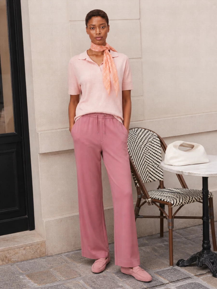 A softly tonal blush story keeps this pairing calm and refined, with the wide-leg trouser echoing the polo’s fluid drape. Dusty-rose loafers keep the line clean while the ivory shoulder bag and peach scarf bring just enough contrast to feel considered rather than matchy. The result is relaxed, polished daywear that moves easily from coffee run to casual lunch without a change of mood.