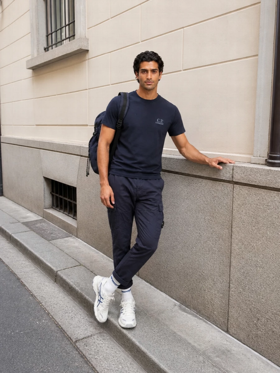 Deep navy on navy keeps this C.P. Company tee and cargo pairing disciplined and urban, with clean lines and subtle tech detailing. Off-white runners and a structured navy backpack lift the palette just enough, so it feels ready for long days on the move without losing that minimalist street-sport attitude.