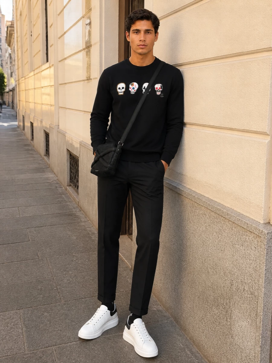 A graphic Paul Smith sweatshirt meets slim black tailoring for a clean, city-ready take on streetwear. Chunky white McQueen sneakers and a compact crossbody keep it sharp and modern without tipping into full sportswear. The result is an easy weekend uniform with just enough attitude from the skulls and logos to feel intentional, not loud.