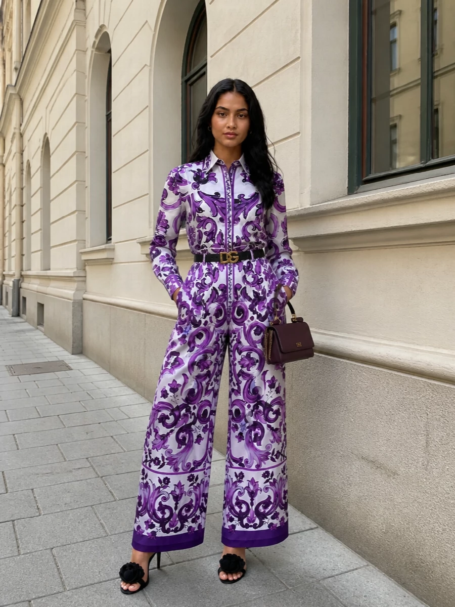 Baroque violet print takes center stage here, doubled on shirt and wide-leg trouser for a confident, almost jumpsuit-like statement. A slim black belt and sculptural stiletto keep the proportions long and clean, while the plum mini top-handle adds a rich, tonal accent that feels glamorous without shouting. The result is romantic Sicilian drama calibrated for city evenings and rooftop parties alike.