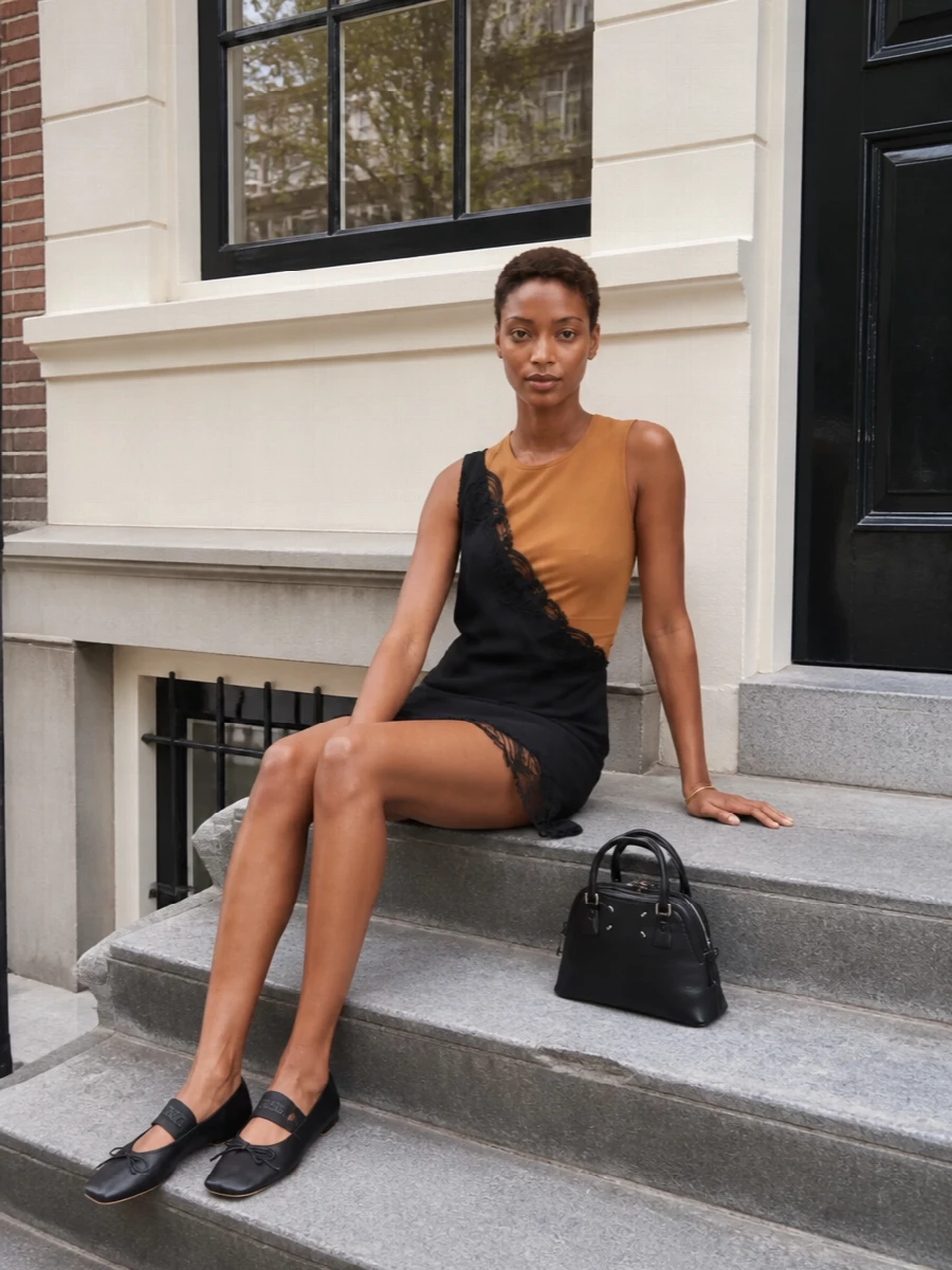 A quietly graphic Margiela ensemble that plays camel against black with asymmetric ease. Bare legs, sharp flats and a compact black bag keep it grounded for summer city days and gallery evenings. The slim gold cuff and scribbled scarf add just enough detail to underline the house’s conceptual edge without softening the clean lines.