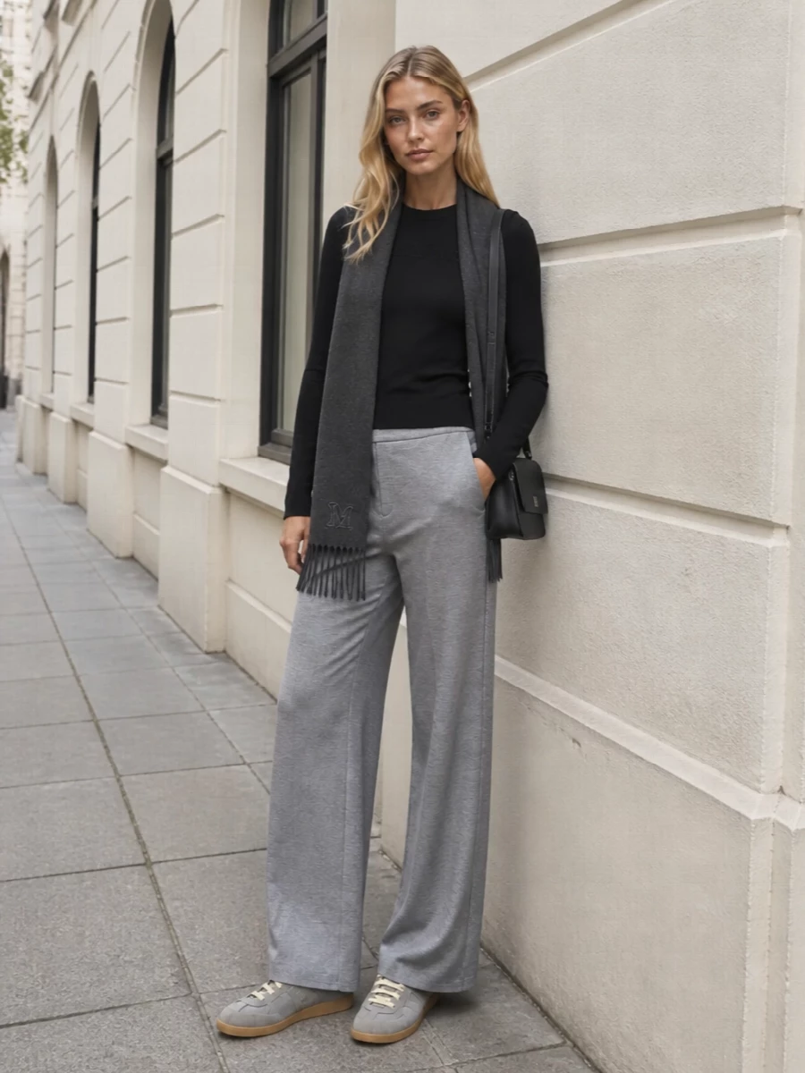 A slim black Max Mara sweatshirt meets heather grey wide-leg trousers for a clean, relaxed take on city dressing. Grey Margiela sneakers keep the line modern and low-key, while a structured black crossbody and charcoal scarf refine the monochrome palette without breaking the quiet mood.
