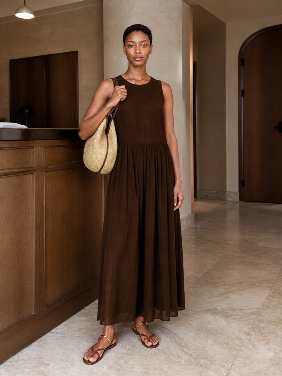 I built around the Uma Wang chocolate maxi so the tote’s woven texture and brown trim feel intentional, not incidental. The long, fluid dress keeps the line simple and boho while the tan leather sandals quietly echo the bag, creating a warm, sun-ready palette you can wear from city mornings to seaside evenings. Opting for the dress rather than separates maintains that easy column and lets texture and tone do the talking.