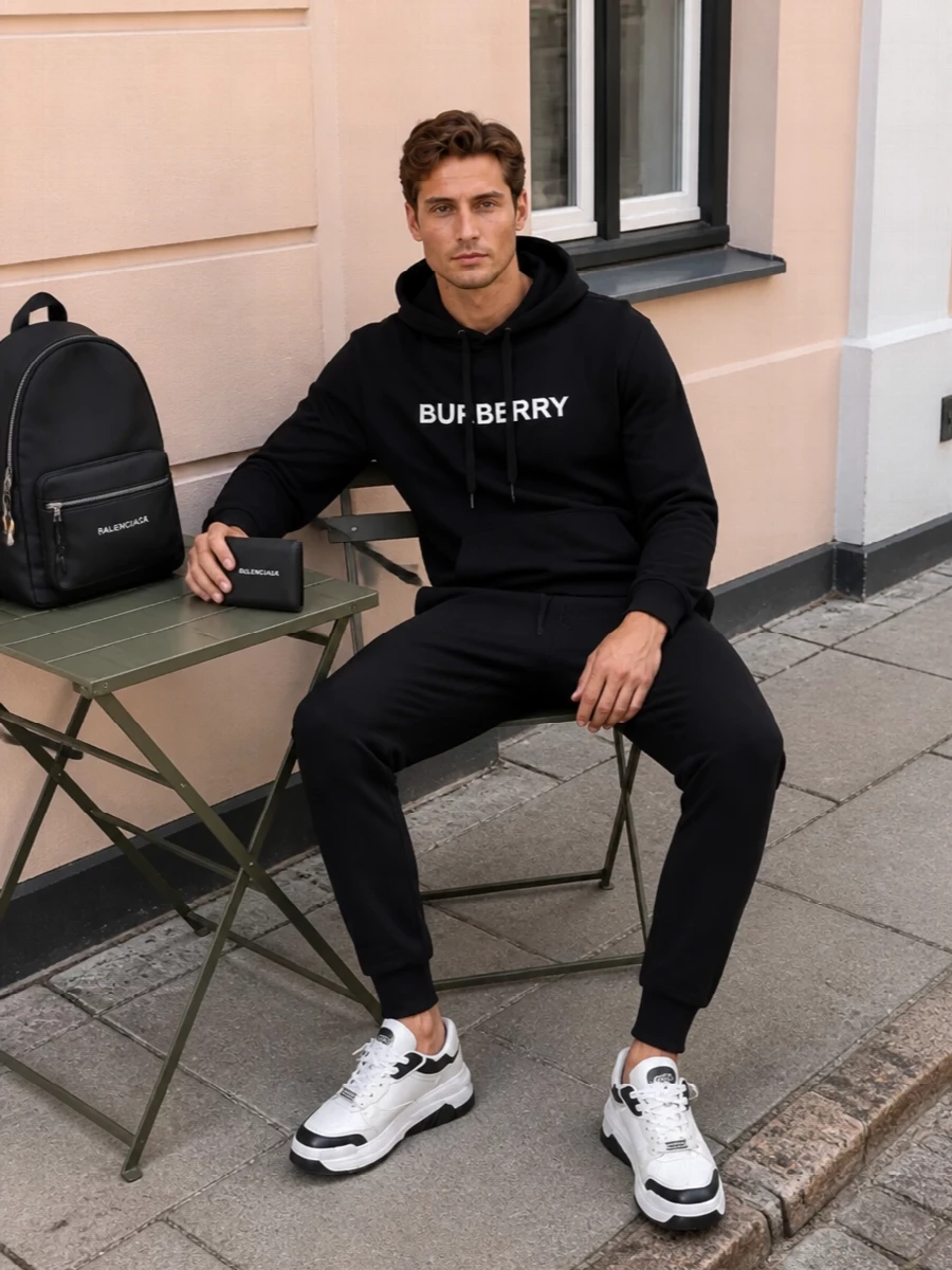 A monochrome city uniform built around sharp logos and sport-driven ease. The Burberry hoodie and joggers pair with sculpted Versace sneakers and a clean backpack, letting the Balenciaga wallet punctuate the palette with its crisp contrast branding. It is relaxed but intentional, ideal for airport runs, weekend circuits, or low-key client coffees where comfort and design credentials need to show up together.