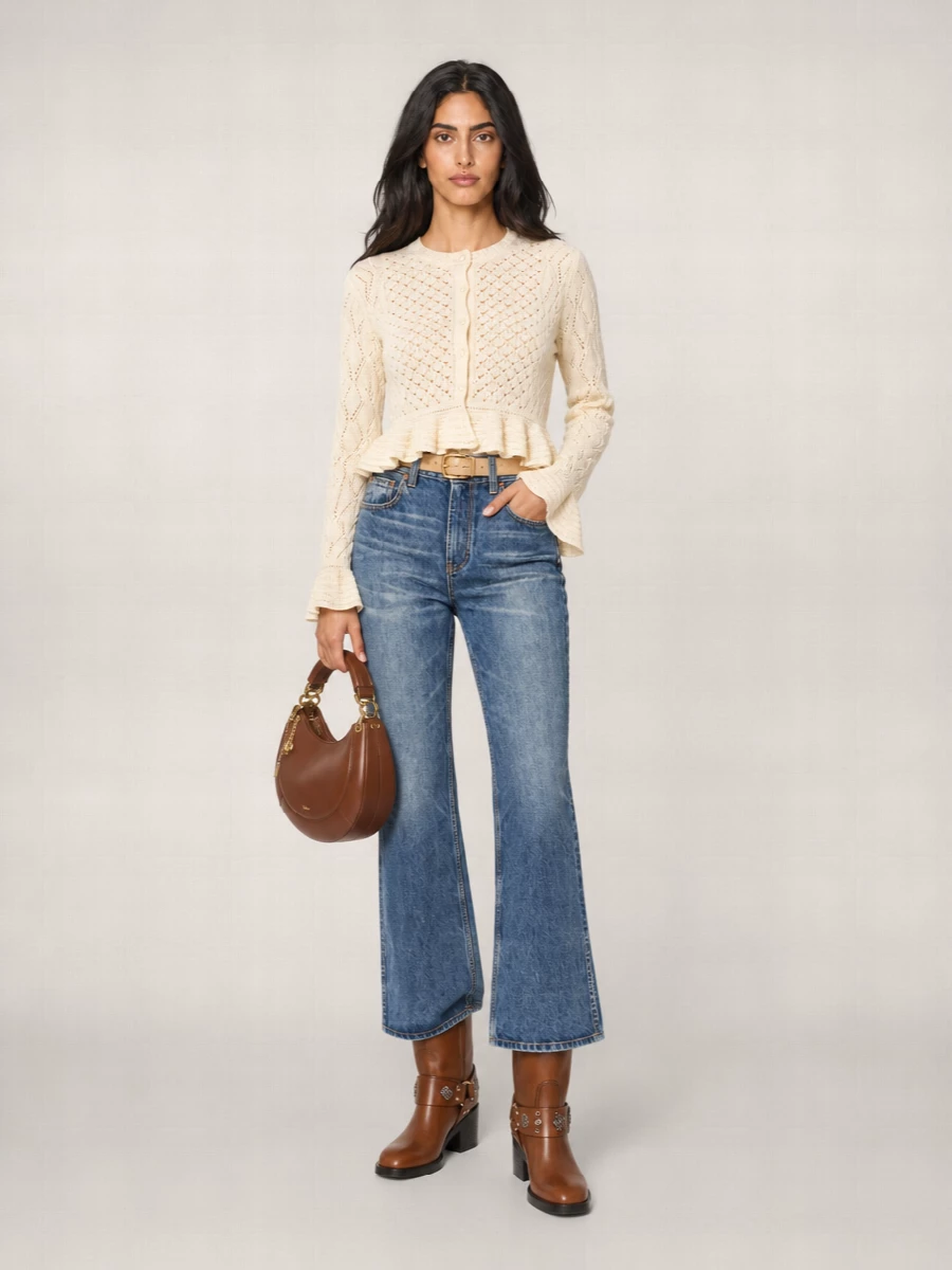 High-rise flared denim meets a buttercream peplum knit for a soft, bohemian take on polished day dressing. Caramel riding boots and a sculpted chestnut shoulder bag keep the palette warm and grounded, while a slim beige belt quietly defines the waist and echoes the gold hardware. It is an easy, long-line silhouette that feels romantic without losing structure.