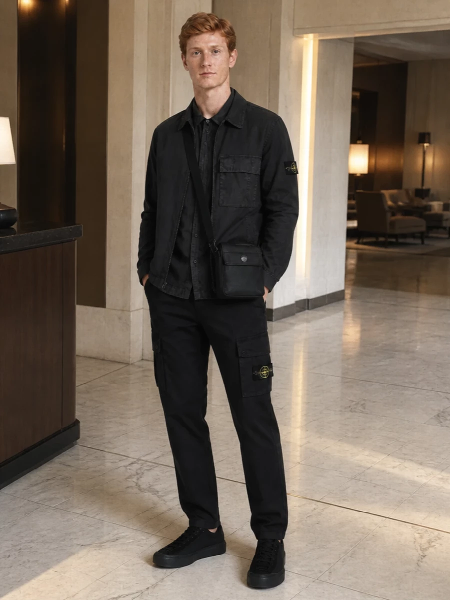 A tight Stone Island story in deep charcoal and black, this outfit leans fully into technical utility without feeling heavy. The short-sleeve layer softens the overshirt’s attitude, straight cargos and black runners keep the line clean, and a compact crossbody finishes it with quiet, urban function.