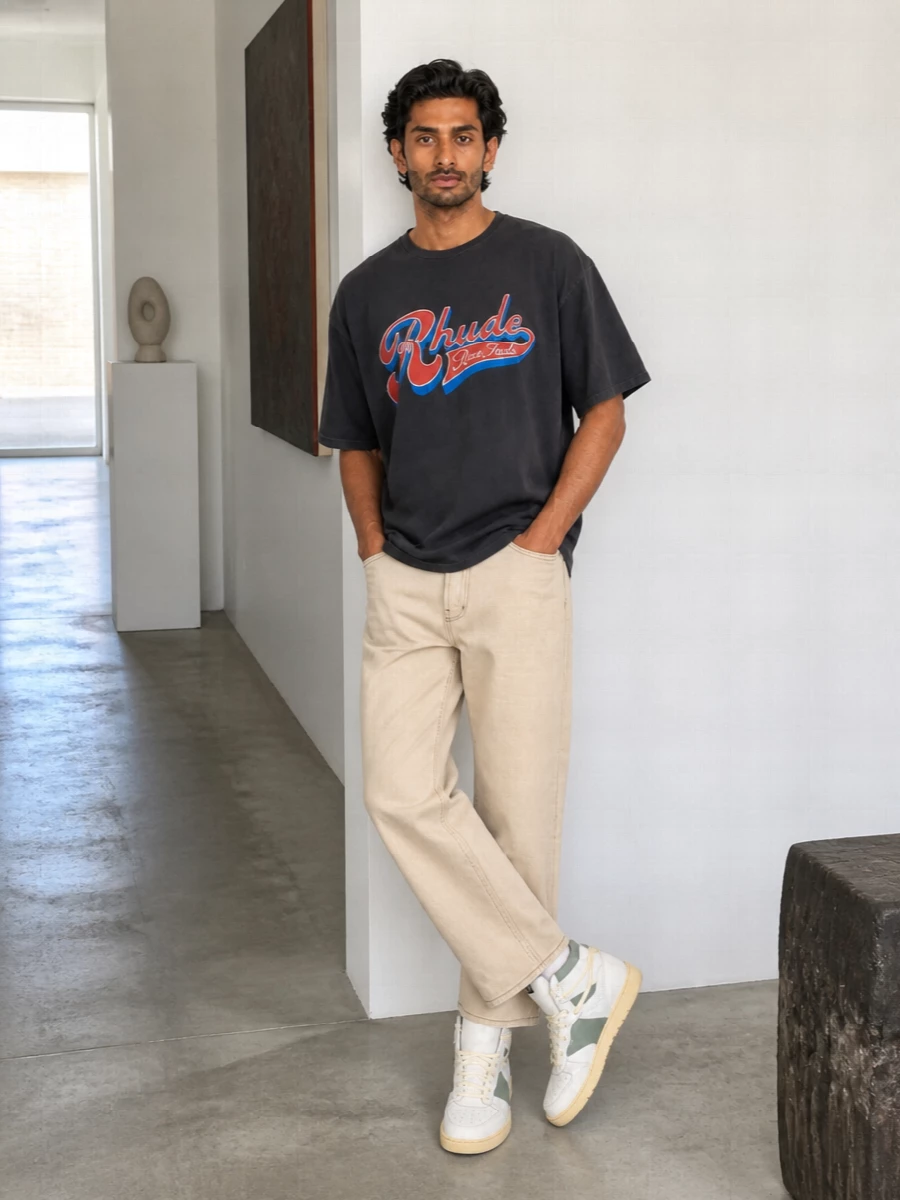 Washed black Rhude graphics sit on top of light beige denim for a cleaner, sun-ready take on race-inspired streetwear. Off-white court sneakers and a softly brutalist tote keep the palette grounded while still feeling energetic. It reads like an off-duty city uniform that can move from day to night without losing the attitude.