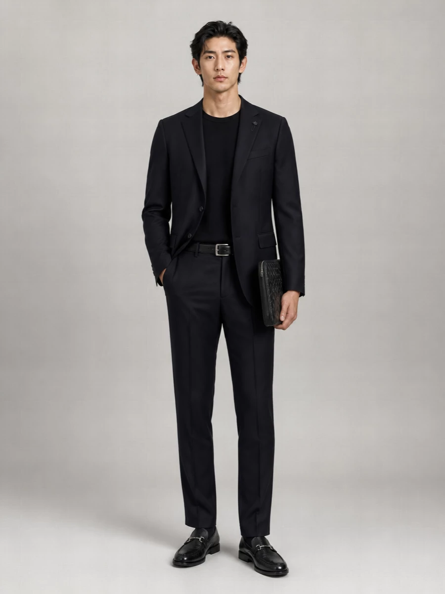 A deep navy Lardini jacket with black tailored trousers creates a precise, modern alternative to the full black suit, still completely appropriate from client meeting to late dinner. Ferragamo loafers and a Bottega Veneta intrecciato portfolio keep the line sleek and international, with the Tod’s belt quietly tying the black accents together. The result is sharp, minimal tailoring that feels composed rather than severe.