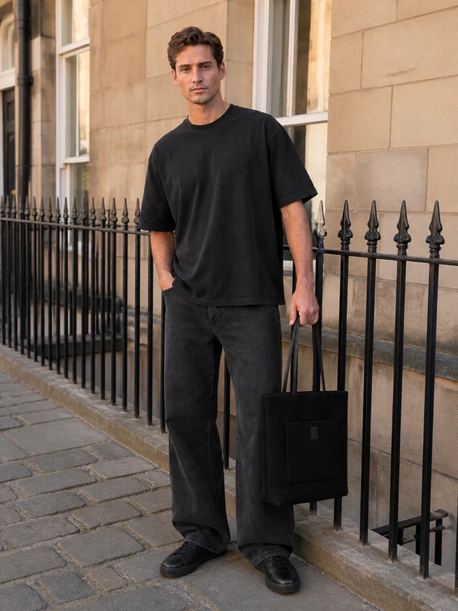 A washed black column of denim and jersey keeps the palette tight and the mood restrained, so the volume of the wide leg feels intentional rather than casual. Low profile black sneakers and a structured tote sharpen the line, reading more gallery afternoon than off duty. It is a quietly confident mix of streetwear and design‑led minimalism that lets proportion do the talking.