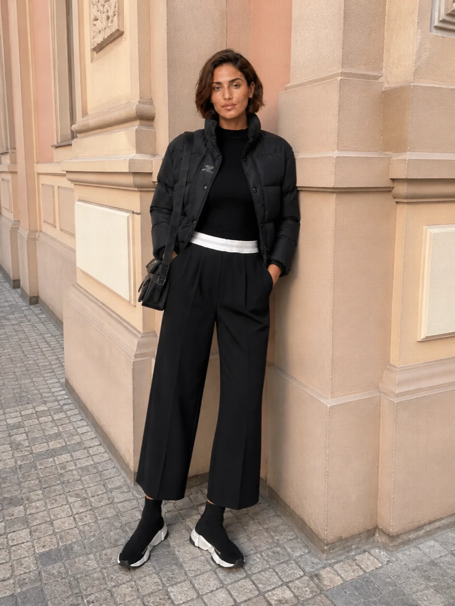 This is a clean, city-ready monochrome ensemble built around the Courrèges cropped puffer, with a second-skin base and architectural volume through the leg. I skipped the dresses and stayed with top and trouser because the jacket’s sport-street energy and crop are made to sit on a high-rise, technical-inspired pant rather than an occasion-leaning mini. Everything from the sock sneaker to the nylon cross-body underscores a modern, graphic urban uniform that feels sharp but easy to live in all year.