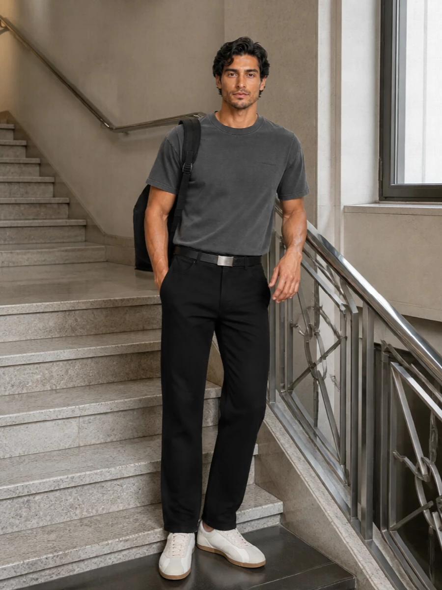Black straight-leg workwear trousers and a washed charcoal tee keep the palette tight and the mood low-key, with subtle texture doing the heavy lifting. Off-white retro trainers break up the dark tones just enough, bringing a softer edge without diluting the utility feel. A slim black belt and clean backpack finish it as a practical, city-ready uniform that still reads considered.