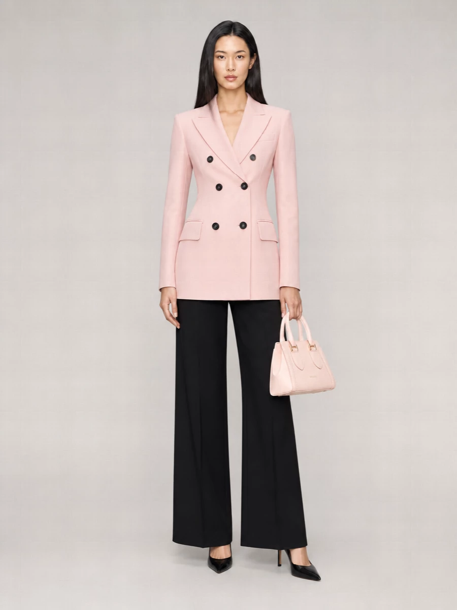 Blush tailoring meets decisive black suiting for a modern, softly feminine take on power dressing. The longline blazer and high-rise wide-leg trouser create one continuous, elongated line, sharpened by a pointed black heel. A structured blush top‑handle bag ties back to the jacket, keeping the palette minimal and quietly polished from client meetings to late dinners.