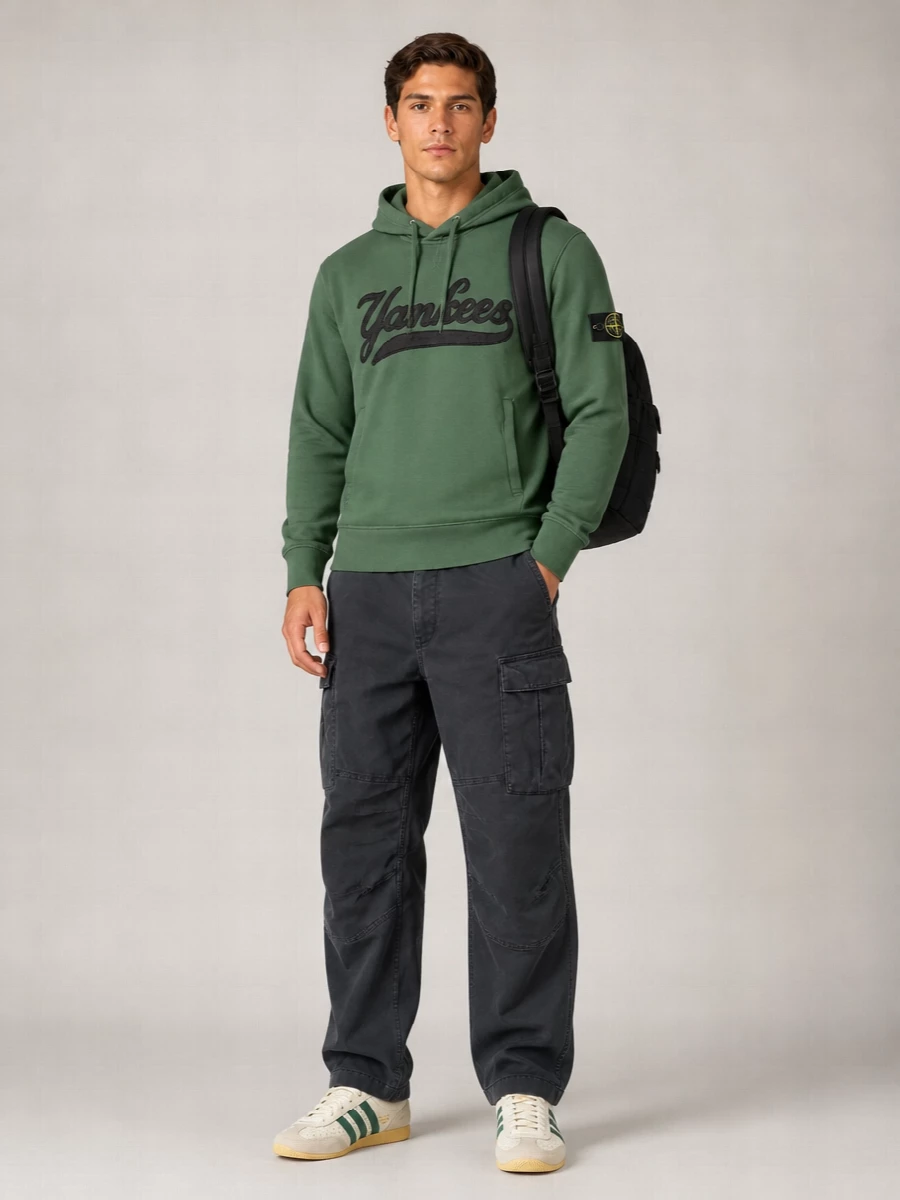 Muted forest green sits against washed charcoal and off-white, giving a calm, technical streetwear energy that still feels pulled together. Relaxed cargos, terrace-leaning sneakers, and a padded backpack keep it ready for city days, from commute to late-night wanderings. The mix of workwear hints and sport details keeps the whole outfit grounded without trying too hard.