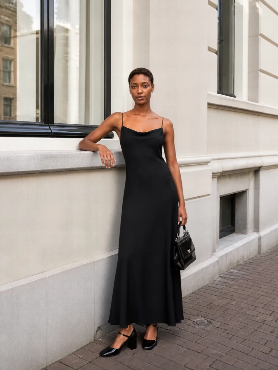 A black slip column keeps the focus on line and movement, picking up the pumps’ round toe and block heel in a similarly sculptural way. Glossy black accessories stay within the same restrained register, so the play of textures does the work instead of extra detail. This path feels more coherent with the shoes’ tailored references than a shirt-and-trouser set, giving you a minimalist evening solution with real quiet drama.