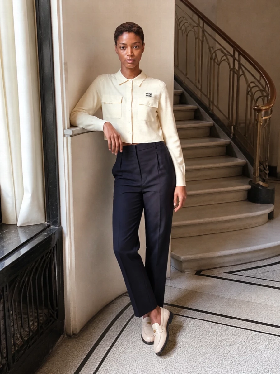 Soft buttercream tones in the loafers and cropped knit are grounded by a clean high-rise navy trouser, giving a precise but relaxed city uniform. The cropped proportion against the long tailored leg keeps it modern and flattering, while the camel structured tote warms the palette without competing with the subtle logo details.
