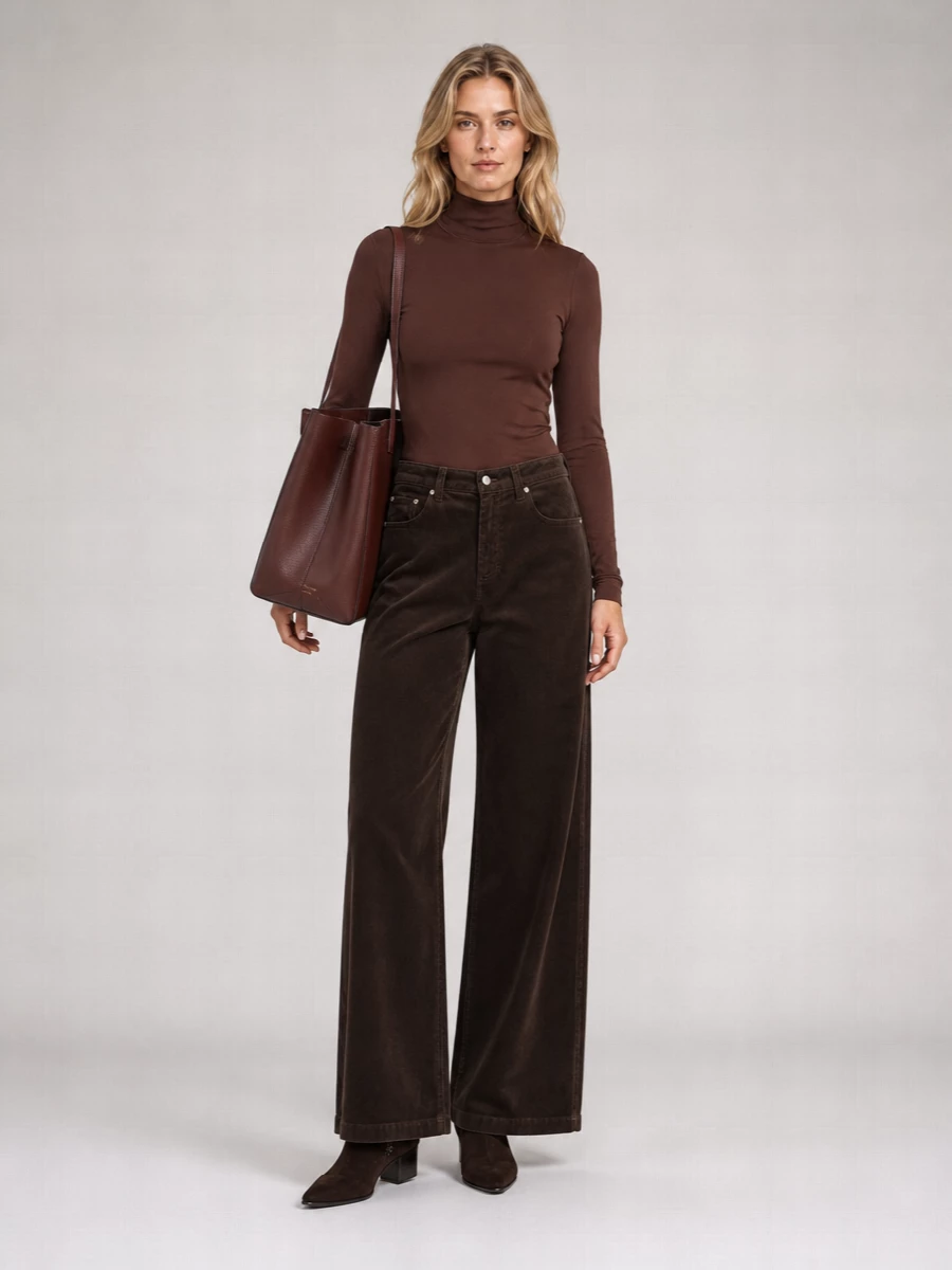 A deep monochrome brown story keeps the wide-leg corduroy feeling intentional and modern, anchored by a second-skin high neck that slips neatly into the high waist. Suede ankle boots sharpen the line just enough, while a structured tote adds polish and function without breaking the minimalist mood. It is a quietly confident outfit for days when you want softness, structure and ease in equal measure.