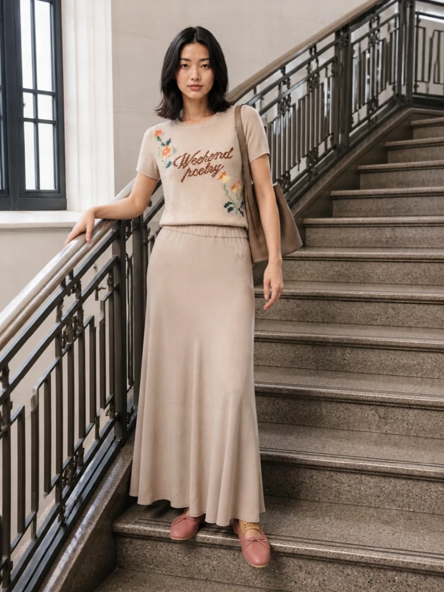 Soft neutrals and a long, fluid line keep this Max Mara knit tee feeling poetic rather than precious. The beige maxi skirt and blush ballet flats echo its warmth and florals, while the taupe bucket bag and whisper‑light scarf add just enough structure for city days and cosy getaways alike.
