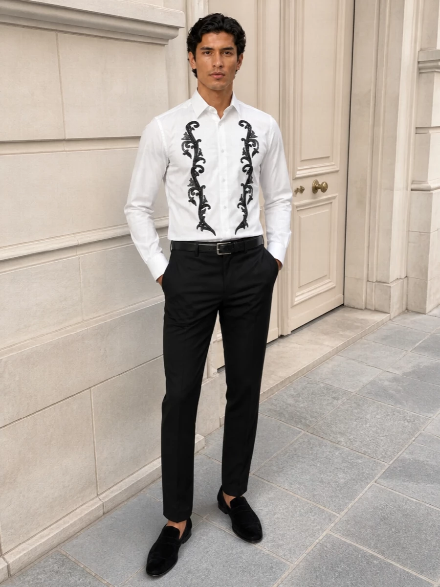 Baroque embroidery becomes the focal point against a disciplined frame of slim black tailoring and tonal velvet slippers. The result is a quietly dramatic evening ensemble that feels polished rather than theatrical. Every supporting piece recedes just enough to let the shirt read as armour for after-dark occasions.