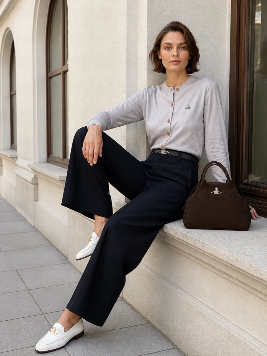 Light grey knit and inky wide-leg tailoring create a clean, elongated line that feels smart without stiffness. Ivory loafers keep it soft and modern, while the dark brown bag and navy belt quietly tie the palette together. It is an office-ready combination that still reads relaxed enough for a late gallery stop on the way home.