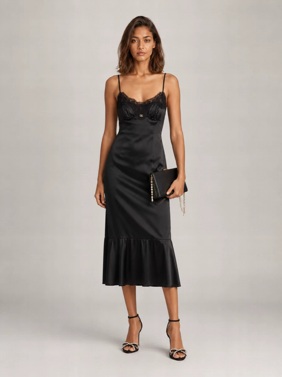 Head-to-toe black satin, lace, and gold details create a quietly dramatic evening ensemble that feels sensual rather than shouting. The crystal-kissed sandals and minimal clutch keep the focus on the slip’s fluid line, while the pearl-chain accessory adds a soft, romantic glint around the edges. It is pure Italian night-time glamour, distilled and controlled.