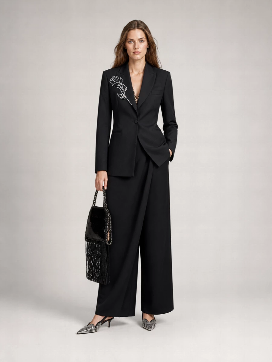 Blumarine’s crystal-rose blazer stays center stage against Max Mara’s sculpted draped trousers, creating a long, romantic column of black with subtle drama in every angle. Coperni’s crystal slingbacks and the sequinned fringe bag echo the lapel embellishment, giving the outfit a cohesive Y2K shimmer that still reads polished and grown-up. The result is evening tailoring that feels sensual, confident and unapologetically glam without a single loud color.