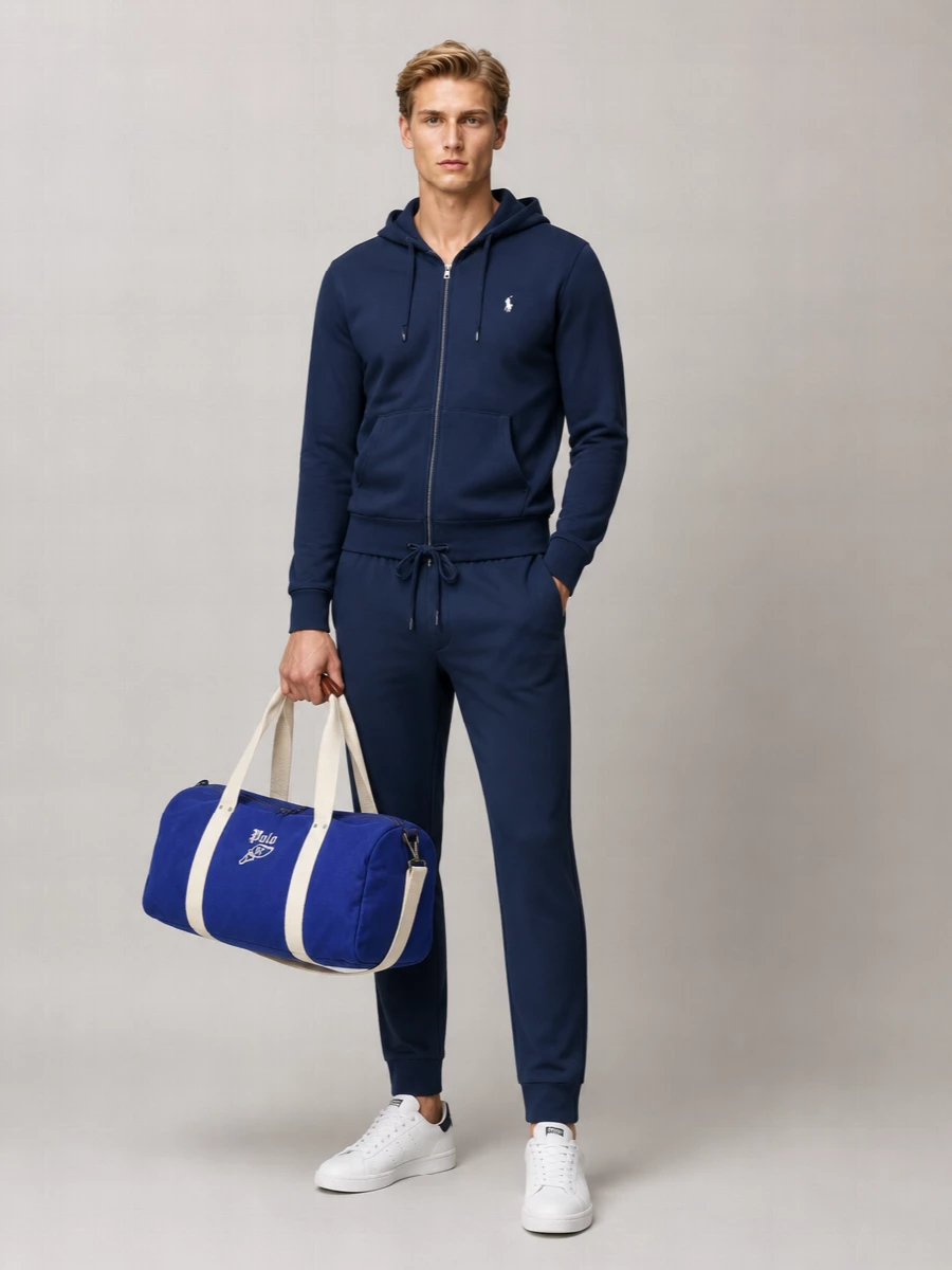 A navy-on-navy Polo pairing keeps the mood clean and athletic, with the straight-leg joggers giving a neater line than classic sweats. White-and-navy court sneakers sharpen the palette and prevent the set from feeling too heavy. The collegiate duffle brings a final hit of sport energy and makes this an easy uniform for travel, gym days or relaxed city errands.