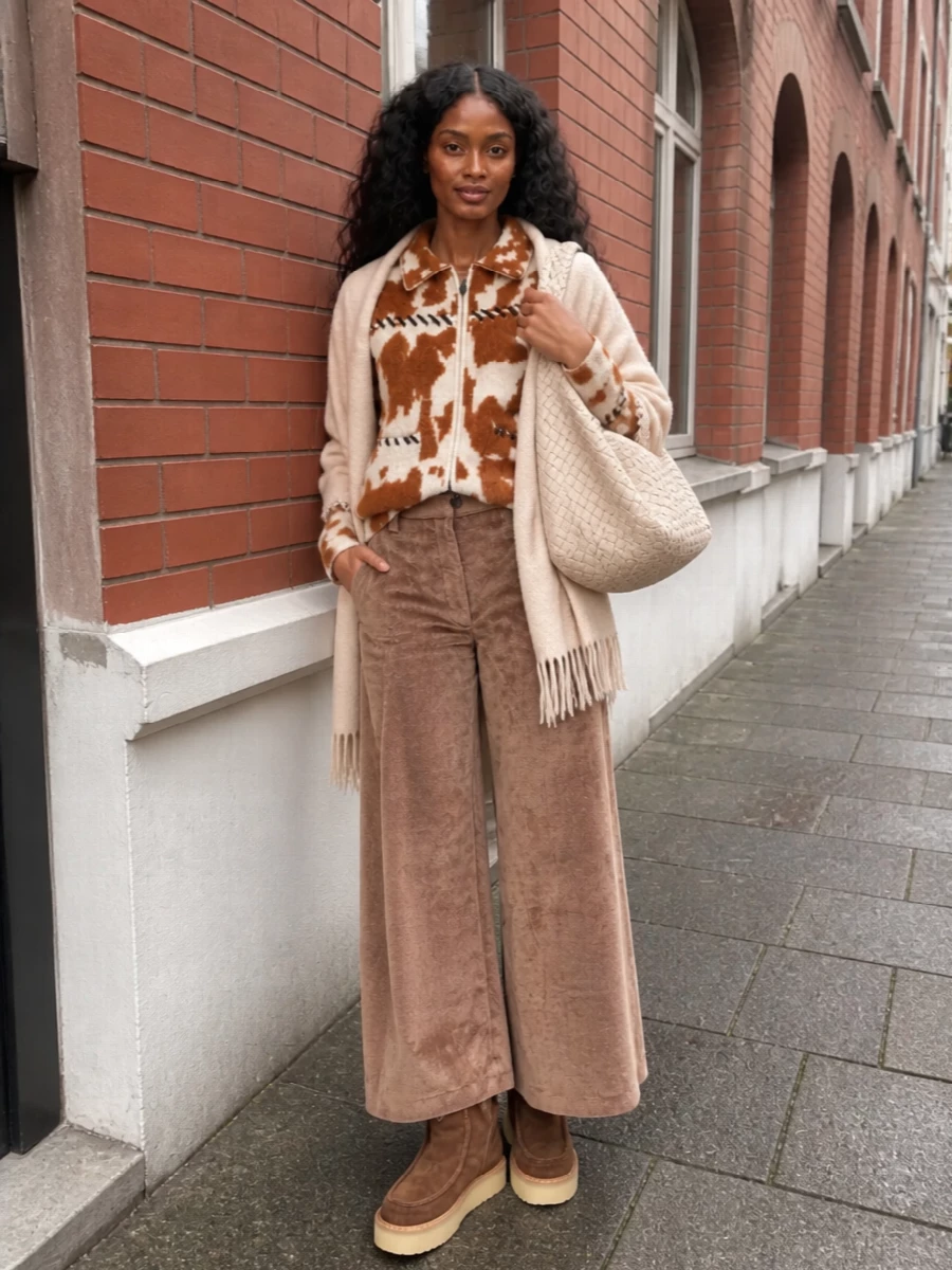 This is cozy city dressing with a grown-up boho tilt: the fuzzy, animal-inspired cardigan sits over plush camel cord wide legs for a long, relaxed line. Chunky shearling-lined boots keep the palette in deep chocolates while adding subtle height, and a slouchy woven hobo plus an oatmeal wrap keep everything firmly in the quiet, tactile luxury space. Tonal browns and creams do the work so the texture and craft can be the focus.