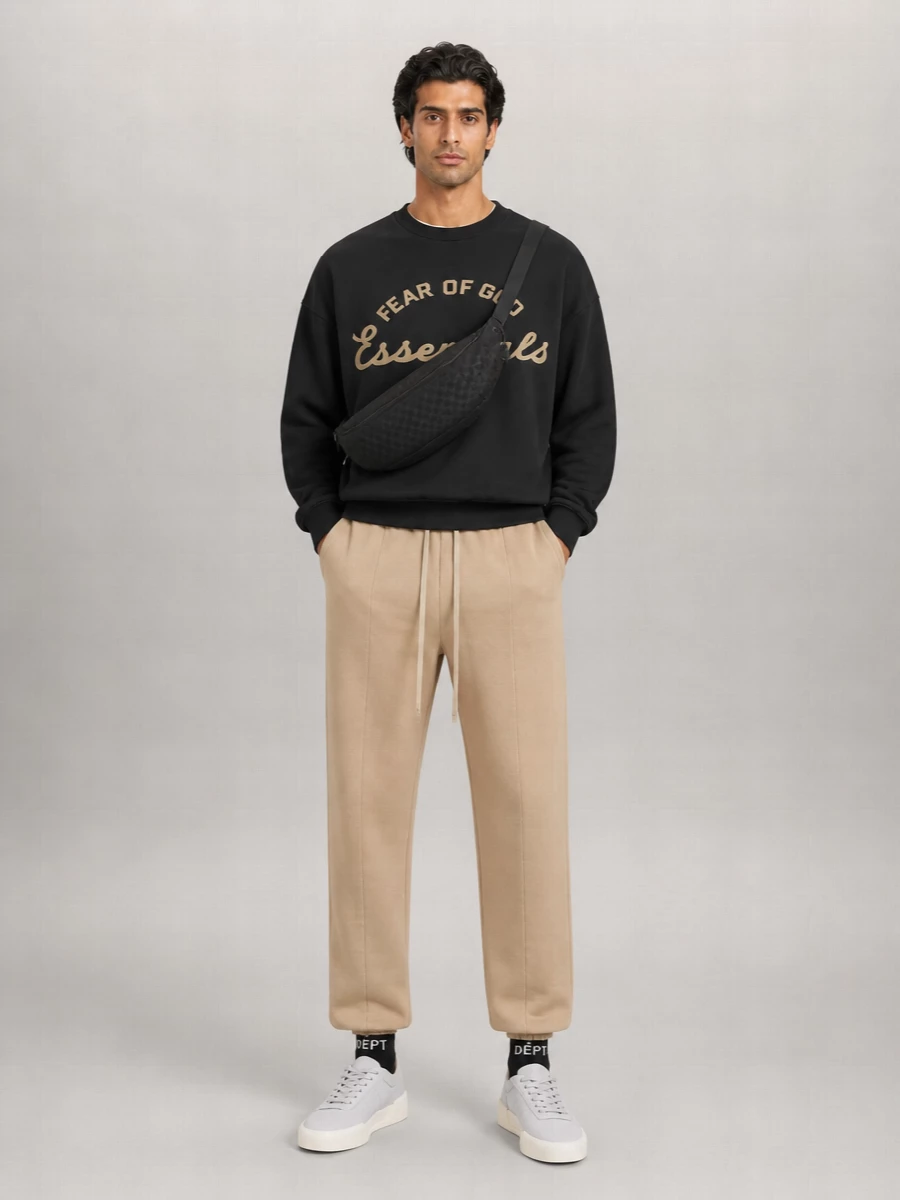 A Fear Of God-on-Fear Of God pairing keeps this grounded in clean, West Coast street energy, with the washed black sweatshirt and camel trouser reading as a sharp two-tone set. Pale grey sneakers soften the contrast at ground level, while the curved Gucci sling and graphic socks bring just enough logo attitude without breaking the minimalist rhythm.