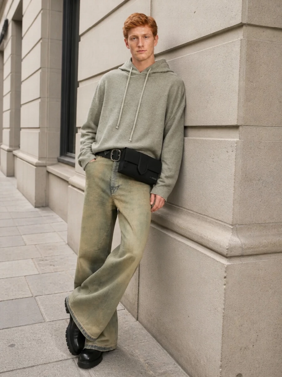 High-rise, scorched-khaki Rick denim flares are anchored by a washed khaki-grey oversized hoodie, creating a cohesive, tonally muted column of volume with that signature dystopian slouch. Black Chelsea boots and a wide black belt inject structure and weight, while a streamlined black belt bag keeps the look practical and urban without diluting the dark, DRKSHDW-driven mood. The result is a fully FW-ready, subversive streetwear uniform that feels intentional yet nonchalant.