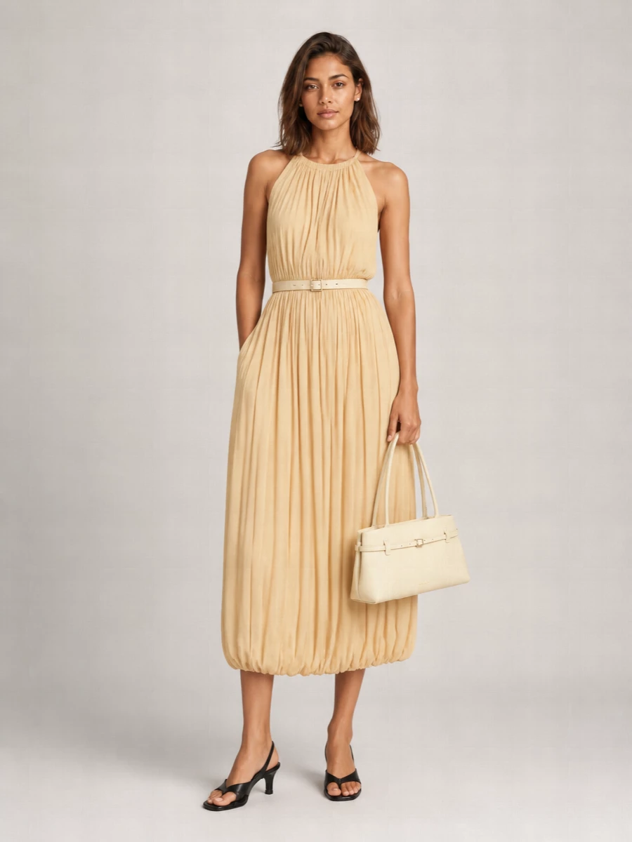 A butter-toned Totême dress sits at the centre, softly structured at the waist and left to move freely through the pleated skirt. Black slingbacks ground the sweetness with a precise line, while the buttercream shoulder bag and pearl studs keep everything in a quiet, romantic register. A slim tonal belt is optional, just sharpening the waist when you want a little more definition for dinner or low-key cocktails.
